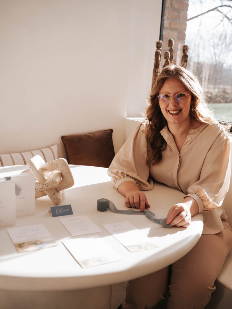 Liesbeth zit aan een ronde tafel met een huwelijksconcept bij haar.